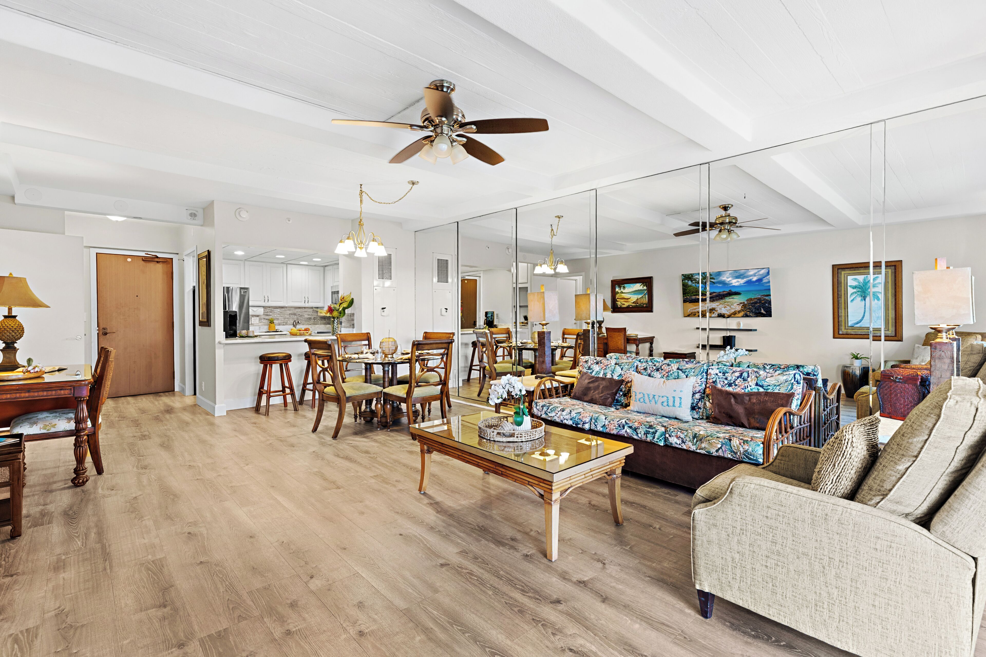 A spacious living area with a dining set, a sofa, and a ceiling fan.