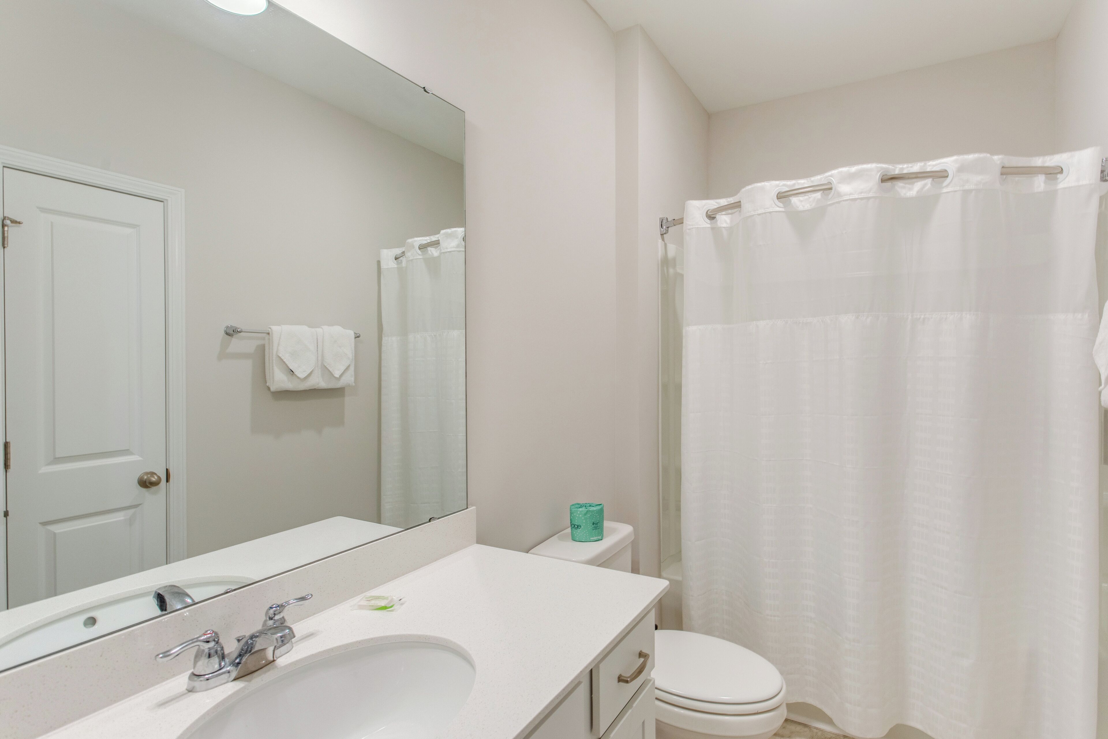 Un baño con lavamanos, espejo e inodoro blancos.