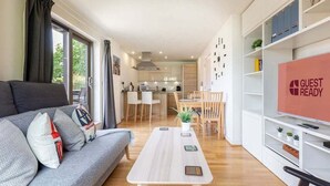 A modern living room with a sofa, a coffee table, and a TV stand with a 'GUEST READY' sign. - GuestReady - Spacious 1BR in East London w Balcony (London)