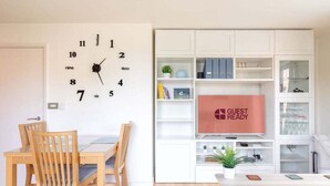 A modern living room with a dining area, a wall clock, and a 'GUEST READY' sign. - GuestReady - Spacious 1BR in East London w Balcony (London)
