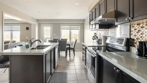 Una cocina moderna con armarios oscuros, una isla central y un comedor con vistas.