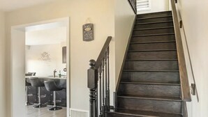 Una escalera con escalones de madera oscura y barandal negro que conduce a un piso superior.