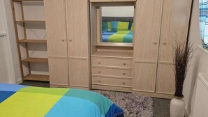 Een slaapkamer met een bed, een kledingkast en een raam.