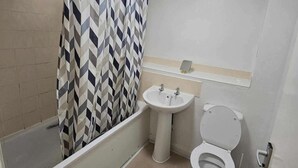Een kleine badkamer met een bad, een wastafel en een toilet.