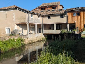A traditional building with a water canal in front, featuring a balcony and a wooden upper floor.