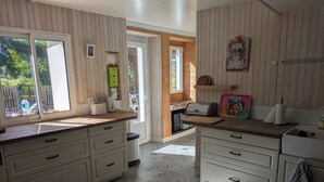 A kitchen with white cabinets, a wooden countertop, and a patterned floor. - Waterfront house - Nature, relaxation & family (Sainte-Marthe)