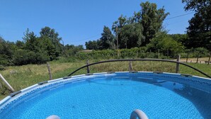 A clear blue swimming pool with a metal ladder leading into it, surrounded by a grassy area and trees. - Waterfront house - Nature, relaxation & family (Sainte-Marthe)