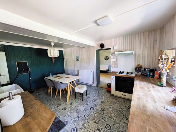 A compact kitchen with a dining area, a small refrigerator, a stove, and a microwave.