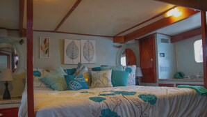 A bedroom with a four-poster bed, a wooden headboard, a mirror, and a dresser.