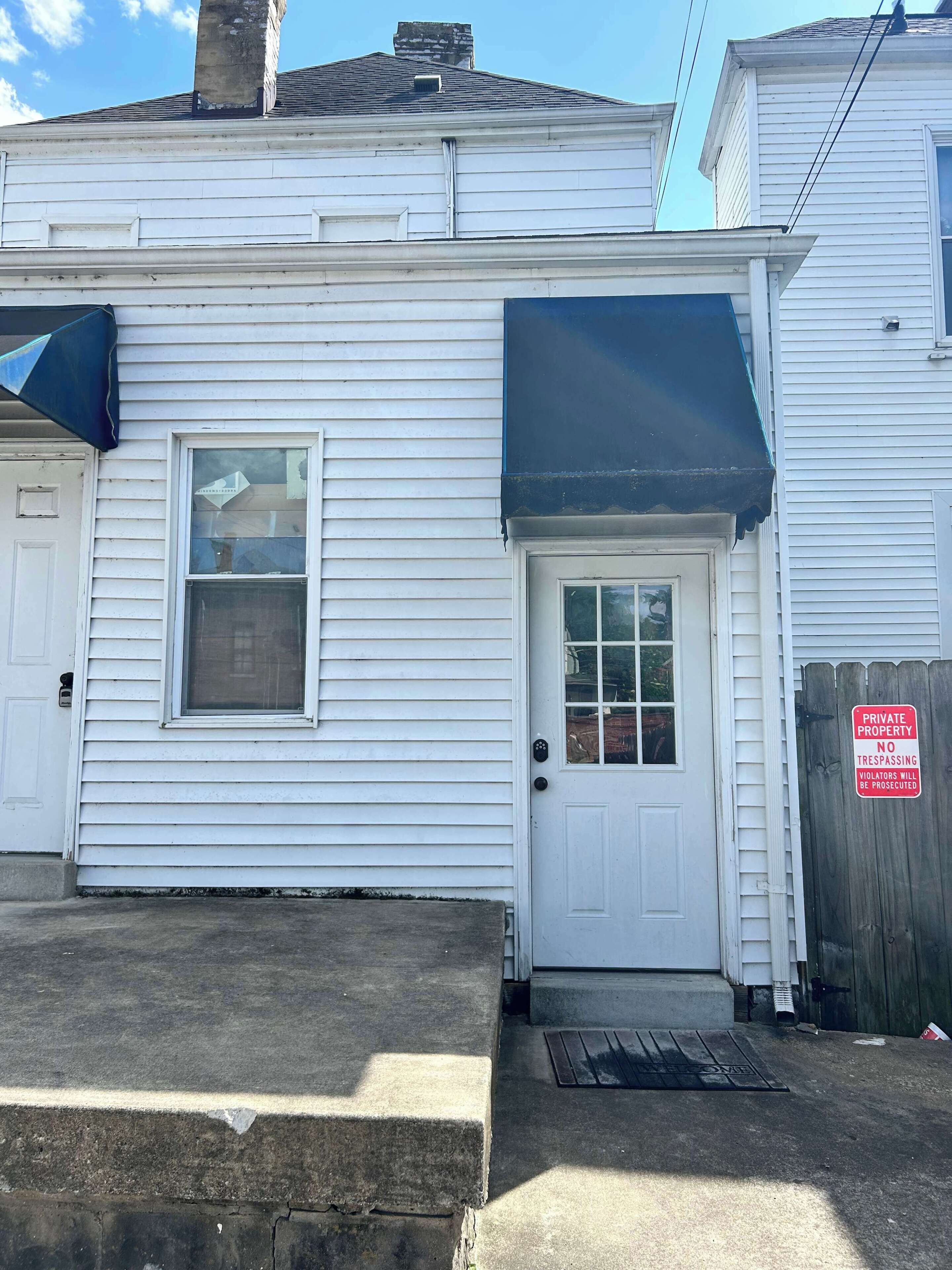 A white single-story house with a front door, a small window, and a porch.