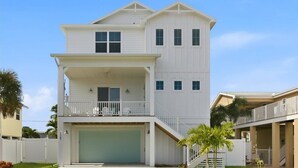 A two-story house with a garage, a balcony on the upper floor, and a staircase leading to the second floor. - Ocean Pearl - Steps from the Beach (Fort Myers Beach)