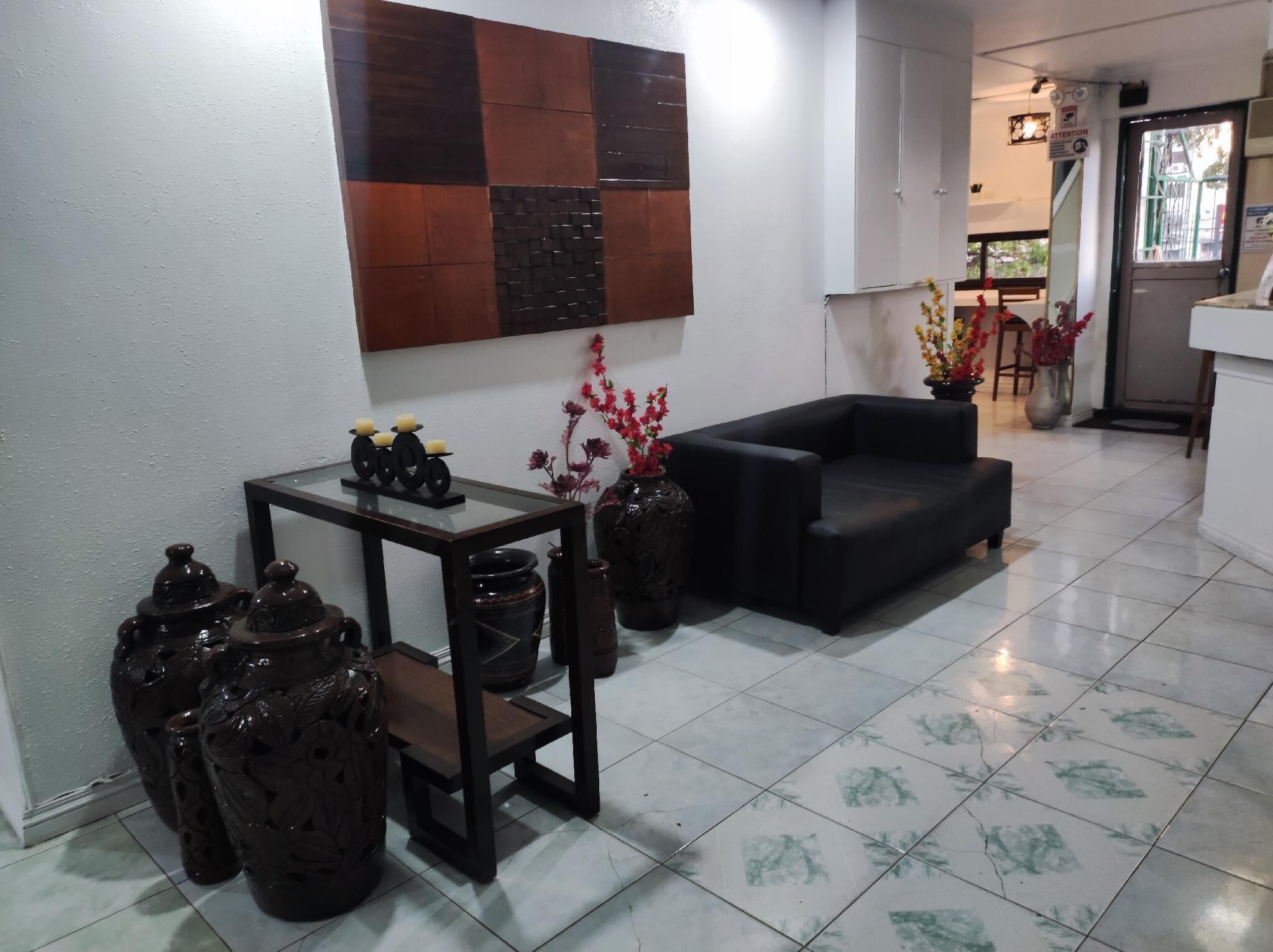A modern living room with a black sofa, a small table with decorative items, and a wall-mounted artwork.