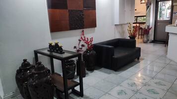 A modern living room with a black sofa, a small table with decorative items, and a wall-mounted artwork.
