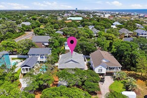 An aerial view of a residential area with houses, trees, and a prominent pink location marker.