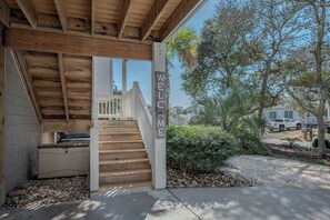 Una entrada cubierta de madera con un letrero que dice 'WELCOME', una escalera y vistas del barrio circundante.