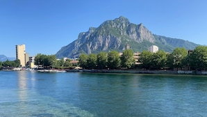 Un lac aux eaux limpides, avec une montagne en arrière-plan et des bâtiments le long de la rive.