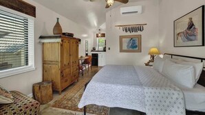 A bedroom with a bed, a wooden wardrobe, a desk, and a chair. - Casa Salvia Rojo - Charming Suite walking distance to Main St! (Fredericksburg)