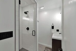 Un baño moderno con cabina de ducha de vidrio, un lavabo blanco y un perchero para toallas.