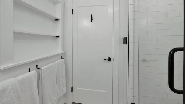 A bathroom with white tiled walls, a white door, and a glass shower enclosure. - Casa Salvia Rojo - Charming Suite walking distance to Main St! (Fredericksburg)