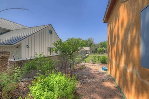A residential area with a white building, a small tree, and a gravel driveway. - Casa Salvia Tejas Suite Walking Distance to MainSt! (Fredericksburg)