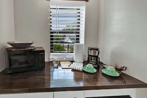 A kitchen with a microwave, coffee maker, and a window with blinds. - Casa Salvia Tejas Suite Walking Distance to MainSt! (Fredericksburg)