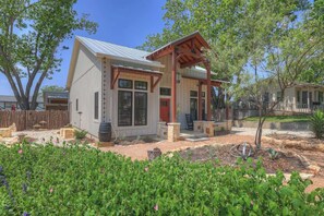 A single-story house with a white exterior, a red door, and a covered porch.