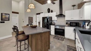 A modern kitchen with a central island, white cabinetry, and stainless steel appliances.
