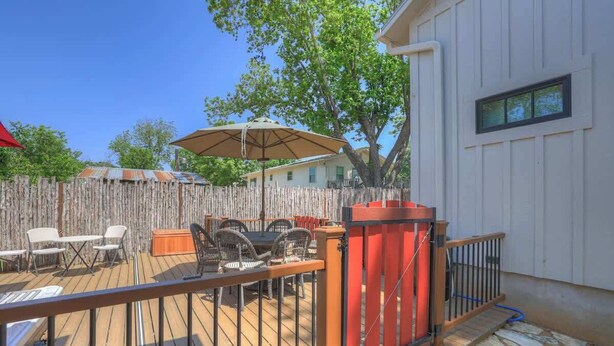A wooden deck with outdoor furniture, a red barrel, and a metal gate.