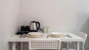 Une table blanche avec une bouilloire, des assiettes, des couverts et des verres.