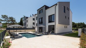 A modern multi-story building with a swimming pool, outdoor seating, and a well-maintained lawn. - Luxury apartment Matic Seaview (Funtana)