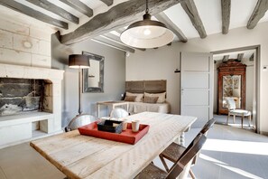 A rustic room with exposed wooden beams, a fireplace, a bed with a wooden headboard, a dining table with a red tray, and a large mirror. - Les Suites Du Cha Teau (Candes-Saint-Martin)