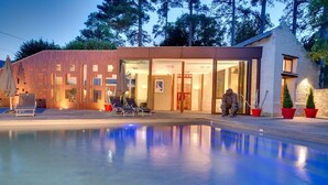 A modern house with a swimming pool, outdoor seating, and a glass-enclosed entrance. - Les Suites Du Cha Teau (Candes-Saint-Martin)
