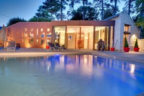 A modern house with a swimming pool, outdoor seating, and a glass-enclosed entrance. - Les Suites Du Cha Teau (Candes-Saint-Martin)