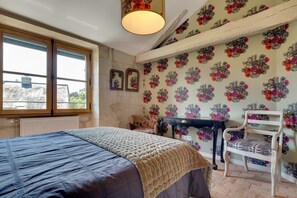 Une chambre à coucher avec un lit, une chaise, une table et une fenêtre.