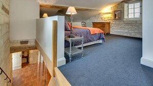 A bedroom with a bed, a nightstand, a lamp, and a stone wall. - Les Suites Du Cha Teau (Candes-Saint-Martin)