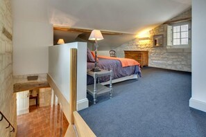 Ein Schlafzimmer mit einem Bett, einem Nachttisch, einer Lampe und einer Steinwand.