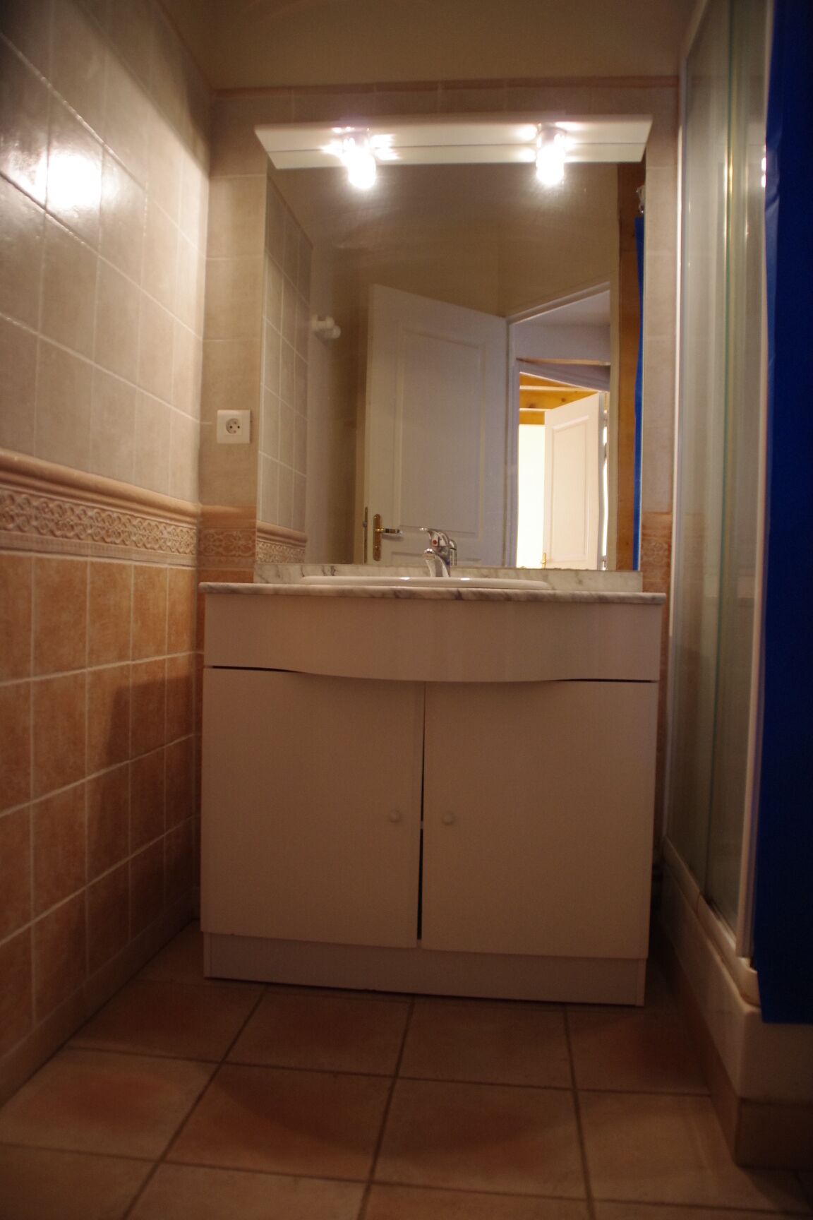 Een badkamer met een wastafel, spiegel en douchegordijn.