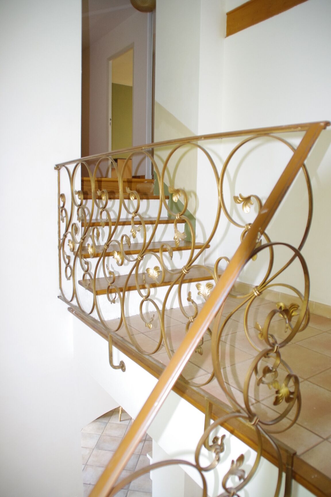 Una escalera con barandillas de metal decorativas y peldaños de madera.