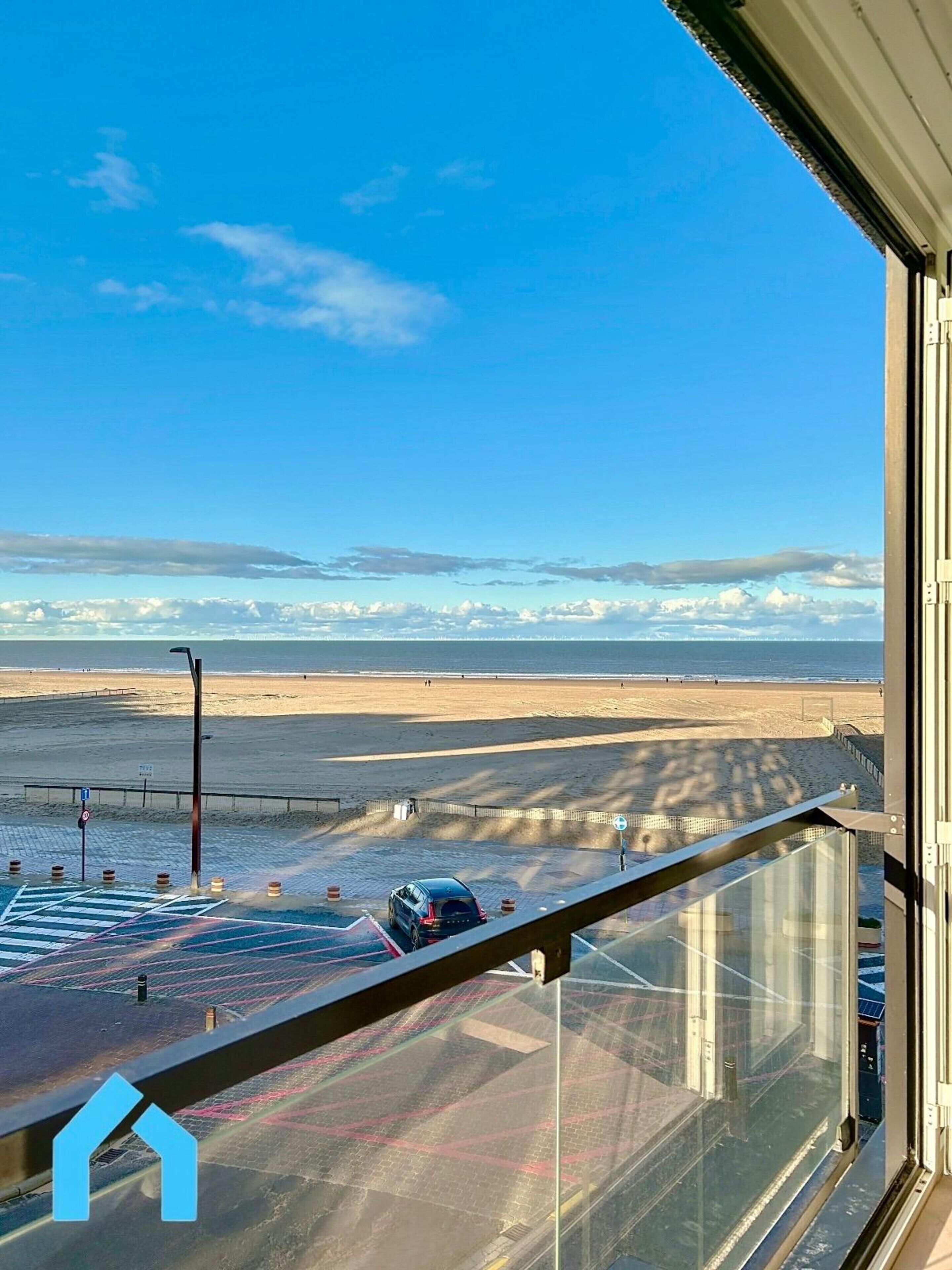 A view from a balcony overlooking a beach with a clear sky.