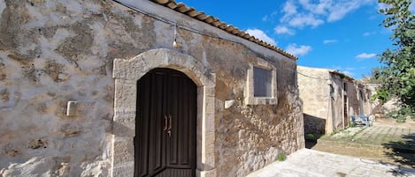 A stone building with a dark wooden door, a small window, and a tiled roof.