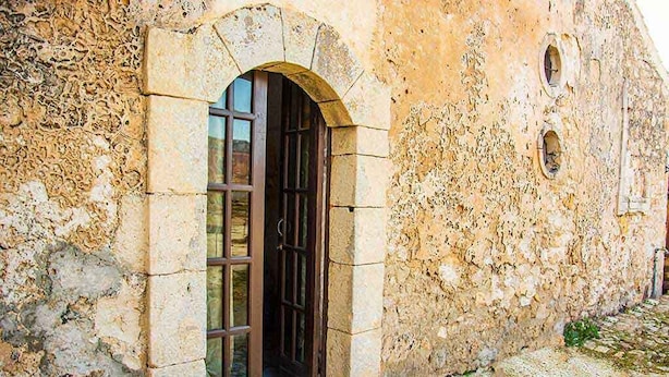 An old stone building with a large arched doorway and a window with multiple panes. - Il Casale Rooms&Apartment (Noto)