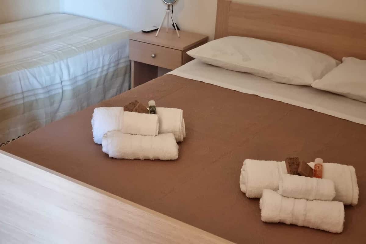 A neatly made bed with rolled white towels and toiletries.