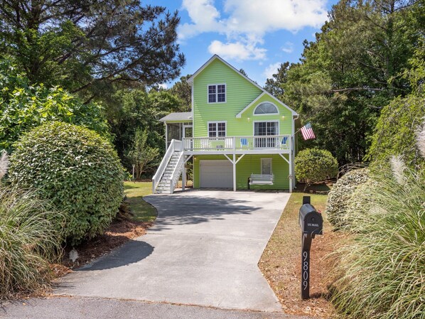 A two-story house with a front porch, a garage, and a mailbox.