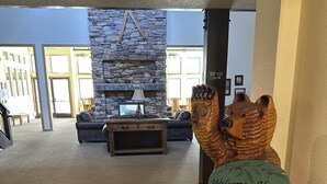 A lobby with a stone fireplace, a wooden bear sculpture, and a 'Welcome Home' sign.