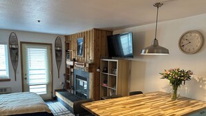 A modern kitchen with a wooden countertop, a built-in microwave, and a television above the stove.