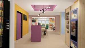 A brightly colored children's library with a central purple counter, bookshelves, and a ceiling light fixture. - Unisotel (Bron)