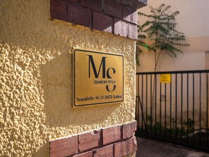 Ein Schild an einer Hauswand mit der Aufschrift 'Modeln Stay' und einer Adresse.