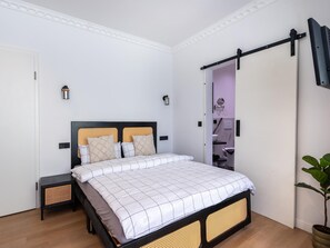 Ein Schlafzimmer mit einem Bett, Nachttischen, einem Kleiderschrank und einer Topfpflanze.