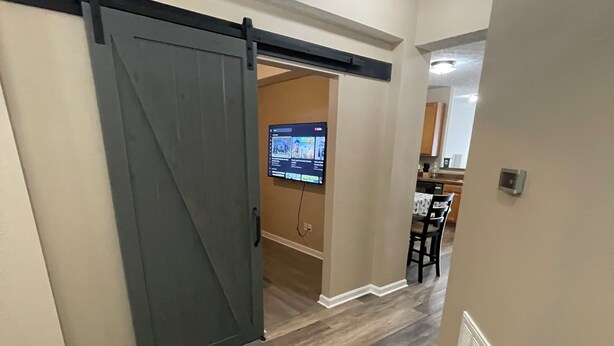 A hallway with a sliding barn door leading to a room with a television. - 3-bedroom townhome in tranquil Delmar with WiFi, AC. Relax and unwind (Delmar)