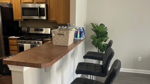 A kitchen with wooden cabinets, stainless steel appliances, a bar area with stools, and a potted plant. - 3-bedroom townhome in tranquil Delmar with WiFi, AC. Relax and unwind (Delmar)